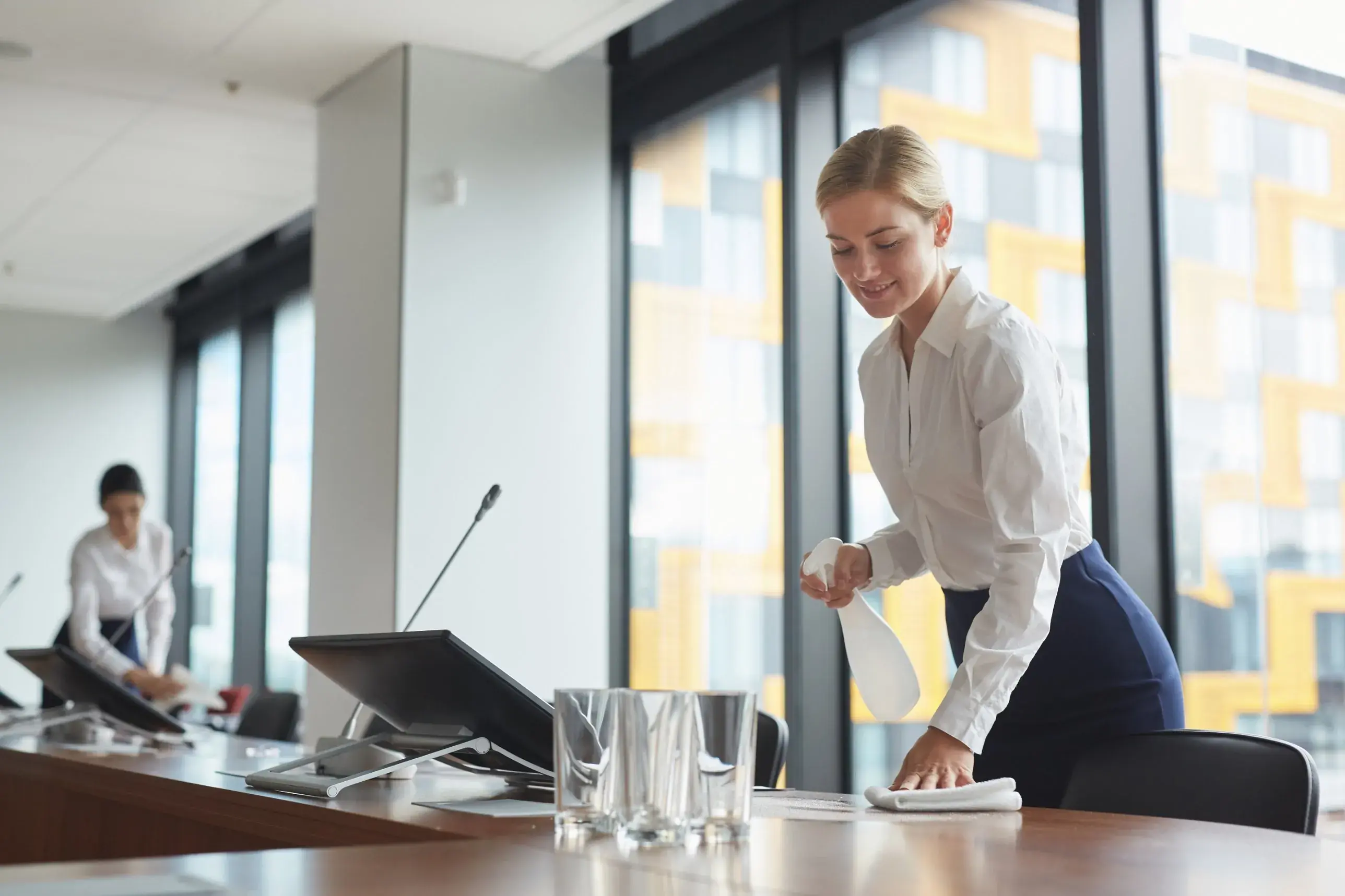 Staff preparing a conference room for a corporate MICE event, placing glasses of water on the meeting table