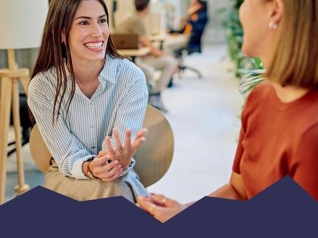 Two women in a friendly conversation in a bright, modern office