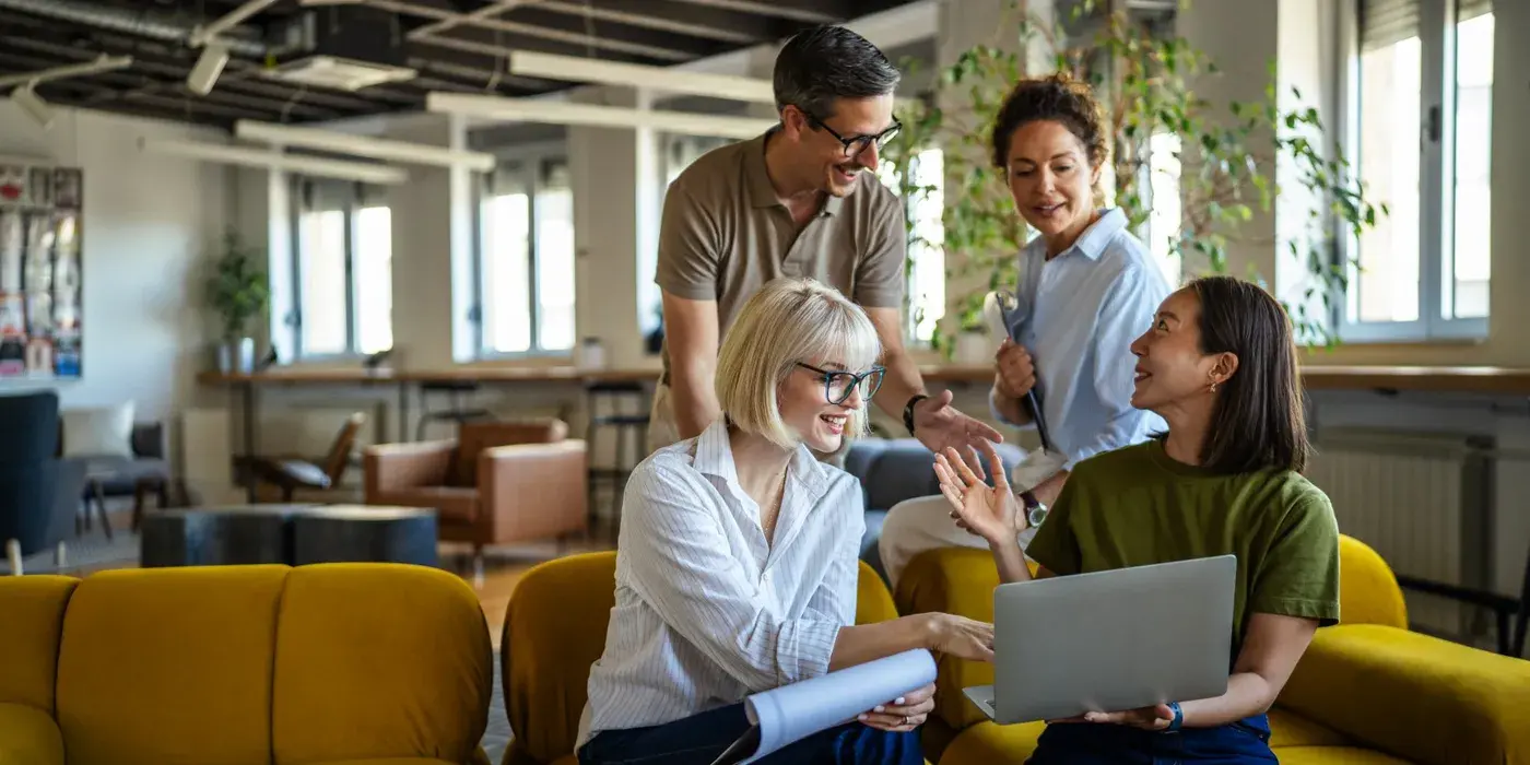 Hotel sales team discussing MICE booking platforms on a laptop in a bright lounge, comparing options to choose the right channel for corporate event RFPs