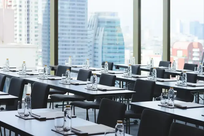 Meeting room in a conference hotel set up in classroom style for a corporate MICE event, with city skyline views