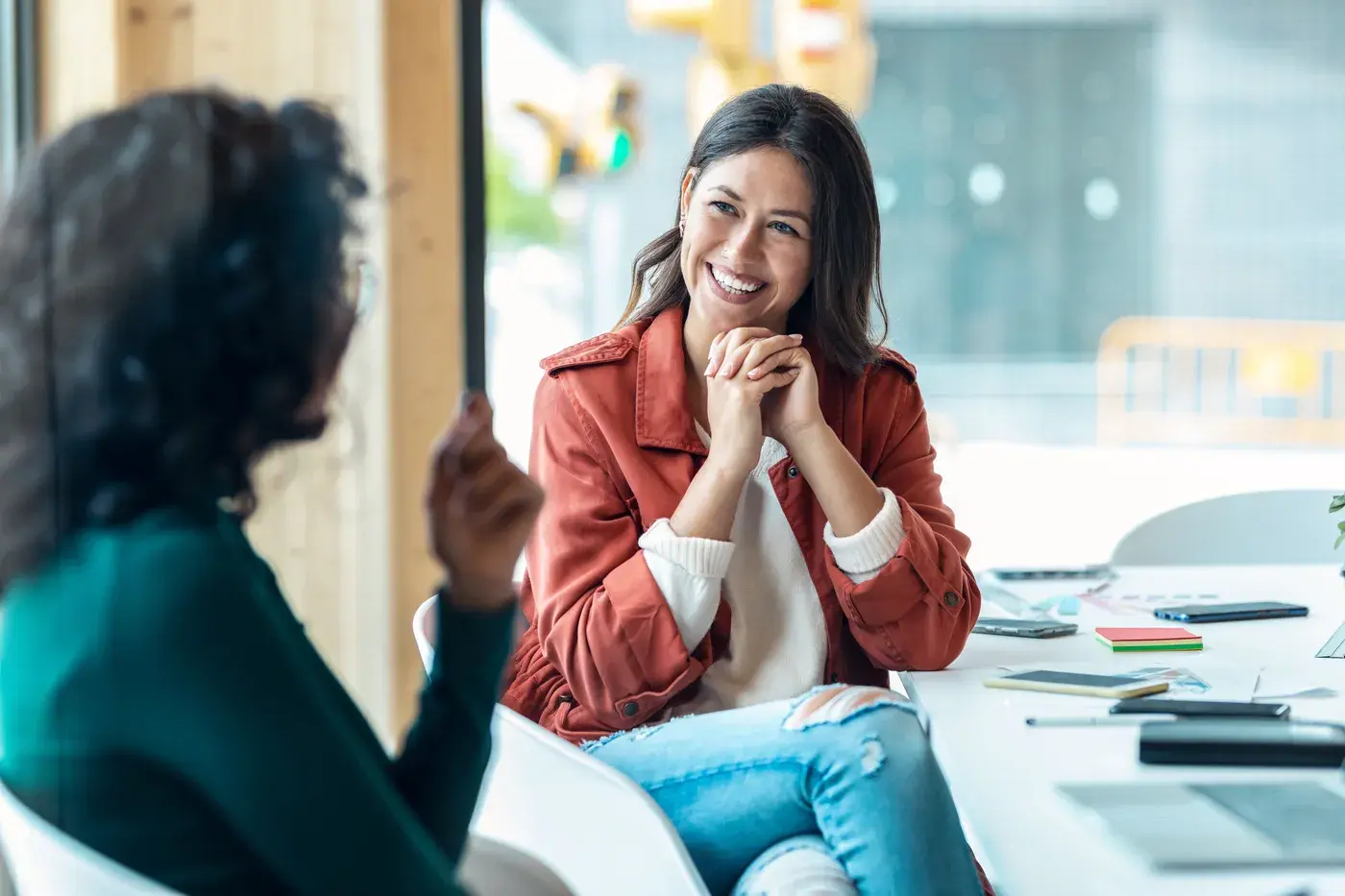 Hotel sales manager in a relaxed personal conversation with a corporate client at a bright meeting table, showing how time saved on structured MICE RFPs goes into building client relationships